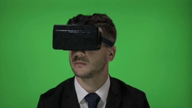 Elegant male candidate experiencing job interview using virtual reality goggle glasses for a sales director position on green screen background