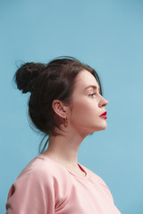 The serious business woman standing against blue background.