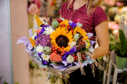 girl holding a bouquet of cornflower, sunflower, dried poppy, chrysanthemum and berries