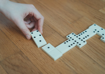 Child playing dominoes on the floor. Close-up view.