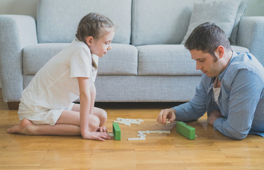 Fototapeta premium Father and daughter playing dominoes at home.