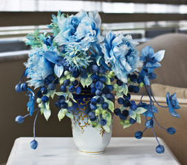 Bouquet with blue large flowers and closed buds. Artificial flowers in a vase for the interior