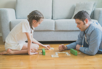 Father and daughter playing dominoes at home.