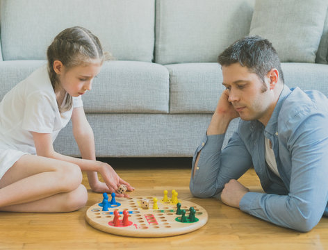 Little girl and her father playing ludo.
