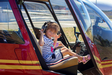 The girl sits at a helicopter steering wheel