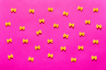 Pattern of pasta farfalle on pink background