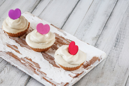 Three homemade raw capkake with cashew cream on a wooden white background. Style rutsik
