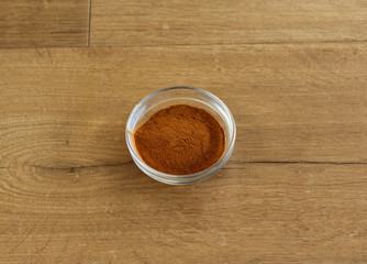 Stone bowl with cinnamon powder on wooden background