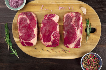 Three slices of raw meat on rustic textures with seasoning