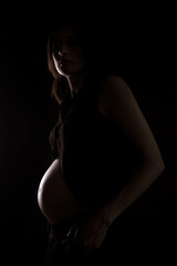 Pregnant woman silhouette over black background