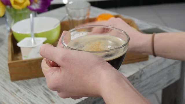 close-up of a young woman's hands drinking a coffee