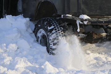the wheel of the car is stuck in the snow. spray of snow from the rotating wheel of winter tires. slipping machine in the snow. the machine is in captivity of a snowdrift after a snowfall.