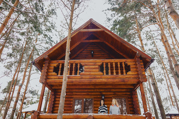 the girls came out of a cottage wooden house on the background of pine trees