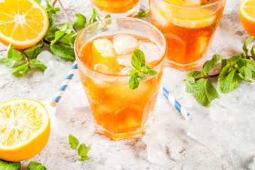 Cold summer drink. iced tea with lemon and mint, on grey stone background.  Copy space