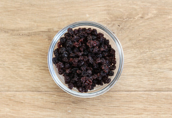 bowl with black dry currants raisins on wooden background