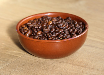 Stone bowl with arabic roasted coffee beans on wooden background