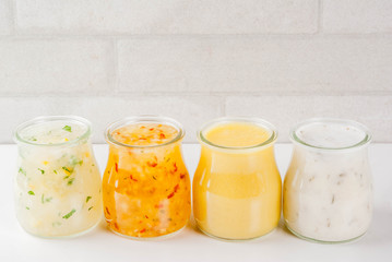 Set of classic salad dressings - honey mustard, ranch, vinaigrette, lemon & olive oil,  on white marble table, copy space
