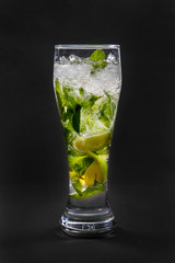 Summer drink with lime and mint, ice on isolated black background. Direct perspective, cool, refreshing