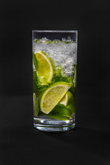Summer drink with lime and mint, ice on isolated black background. Direct perspective, cool, refreshing