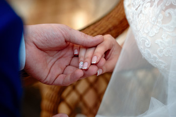 Bride and groom holding hands close up