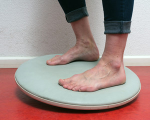 closeup of feet under blue jeans on balance board on red floor
