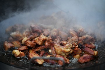 chopped pieces of pork fry in oil outdoor