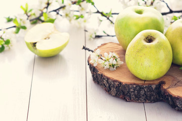 Ripe green apples with spring flowers on a white wooden background. Toned Vintage Effect