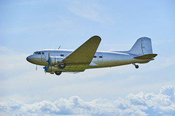 Fototapeta na wymiar Old propeller airliner flying in cloudy sky 