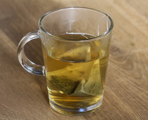 Glass of green tea with tea bag on wooden background