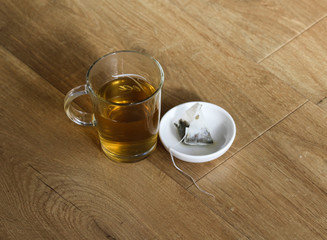 Glass of green tea with tea bag on wooden background