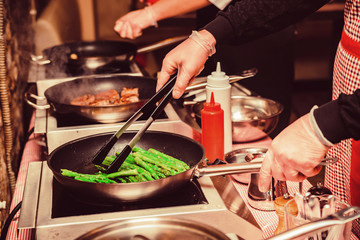 Preparing green asparagus in frying pan