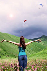 Girl is looking at the paraglider in the mountains
