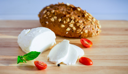Sliced mozzarella with cherry tomato, basil and cereal bread