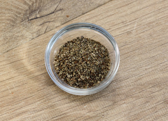 Glass bowl with fresh sliced marjoram herbs on wooden background