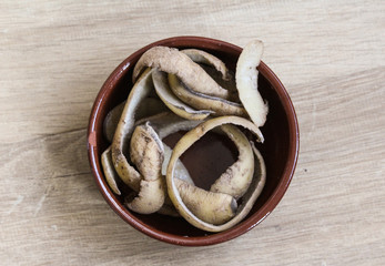 Stone bowl with potato peels on wooden background