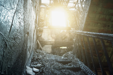 Interior of burnt by fire building. Burned wooden staircase in sun light