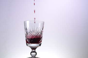 Red wine glass with red wine pouring