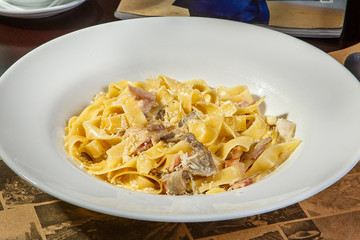 Pasta, noodles with bacon and mushrooms, decorated with cheese. Side view. Serving a meal in a cafe, restaurant