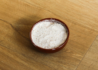 Stone bowl with wheat flour on wooden background