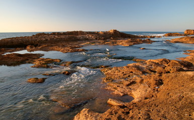 Pejzaż ze skalistym brzegiem morza, płytką zatoczką między skałami, morskimi ptakami, za...