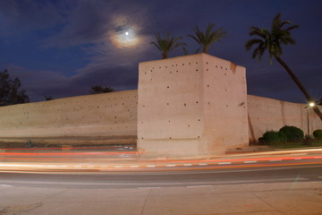 Widok nocnego Marrakeszu w Maroku, zabytkowy mur wokół medyny, palmy, poświata księżycowa,...