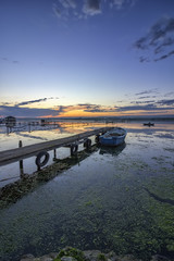 exciting twilight on a shore with pier and boat. Vertical view