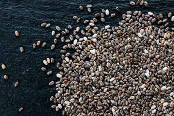 Chia seeds on black slate background, top view, macro