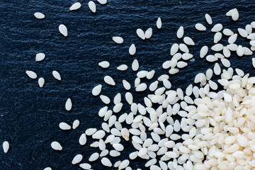 Fototapeta premium sesame seeds on black slate background, top view, macro
