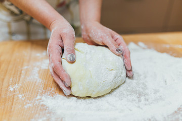 Hands baking dough on wooden table