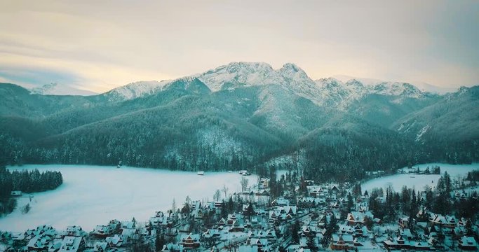 aerial view of a small snowy town and mountains in winter