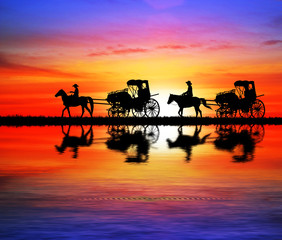 Fototapeta na wymiar silhouette Vintage carriage and horse water reflection on sunset background