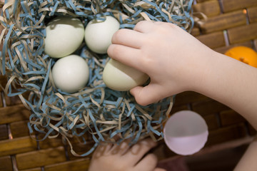 child's hands holding eggs in a paper nest and a cup as a symbol of easter