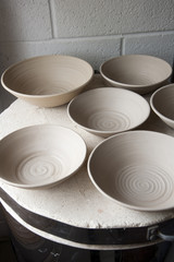 Work in progress standing on the top of the kiln in a ceramics artists home pottery studio. Stoneware bowls, turned, dried and ready to fire.