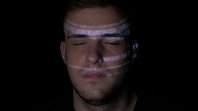 Young ai artificial intelligence IT student memorizing programming code for his exam late at night with eyes closed and reflected digital data on his face